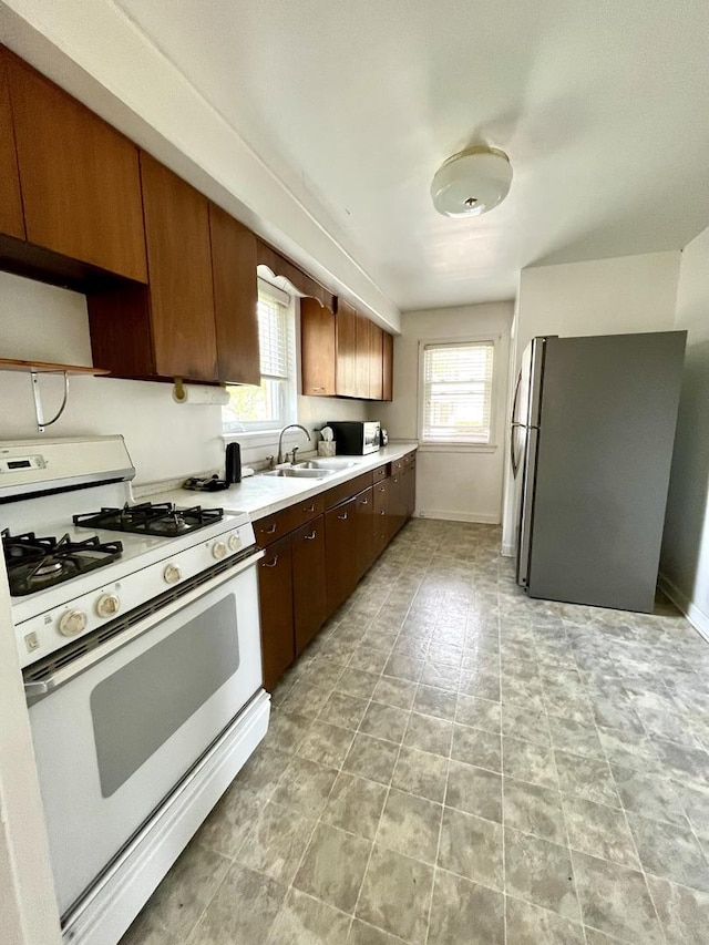 1140 Blanchan Ave, La Grange Park, IL 60526 - kitchen with white range with gas stovetop, freestanding refrigerator, a sink, light countertops, and healthy amount of natural light