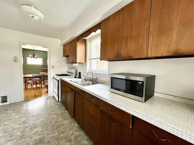 1140 Blanchan Ave, La Grange Park, IL 60526 - kitchen featuring gas range gas stove, stainless steel microwave, a sink, light countertops, and a chandelier