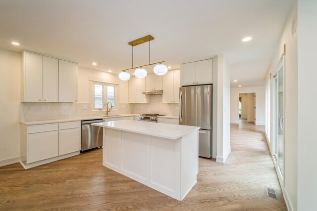 2240 Vista Ct, Northbrook, IL 60062 - kitchen with stainless steel appliances, a kitchen island, white cabinetry, tasteful backsplash, and light wood-style floors
