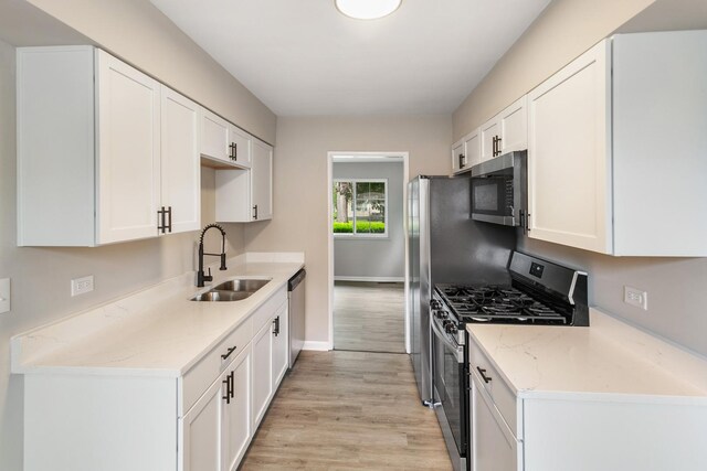 17303 Chicago Ave, Lansing, IL 60438 - kitchen with appliances with stainless steel finishes, a sink, light wood-style flooring, white cabinetry, and baseboards