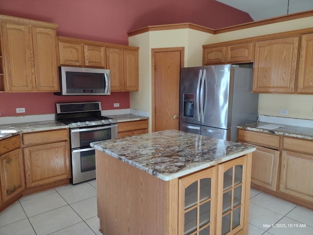 41 Manor Dr, Matteson, IL 60443 - kitchen featuring stainless steel appliances, light stone counters, a center island, glass insert cabinets, and light tile patterned floors