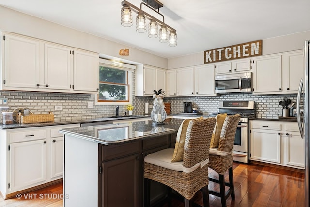 1006 Tristram Ct, West Dundee, IL 60118 - kitchen with stainless steel appliances, dark wood finished floors, white cabinets, a kitchen island, and backsplash