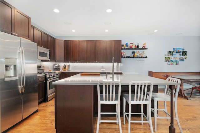 1828 N California Ave, Chicago, IL 60647 - kitchen featuring stainless steel appliances, a breakfast bar, light countertops, recessed lighting, and a center island with sink