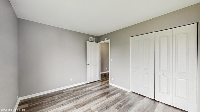 154 Wildflower Ln, Round Lake Beach, IL 60073 - unfurnished bedroom featuring wood finished floors, baseboards, and a closet