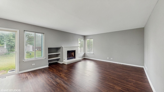 154 Wildflower Ln, Round Lake Beach, IL 60073 - unfurnished living room featuring dark wood-style floors, baseboards, and a brick fireplace