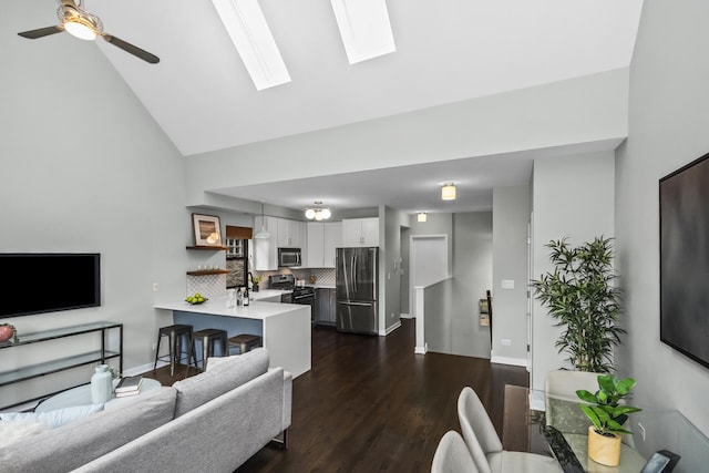 2035 W Crystal St Unit 3, Chicago, IL 60622 - living room with high vaulted ceiling, dark wood-style flooring, a ceiling fan, a skylight, and baseboards
