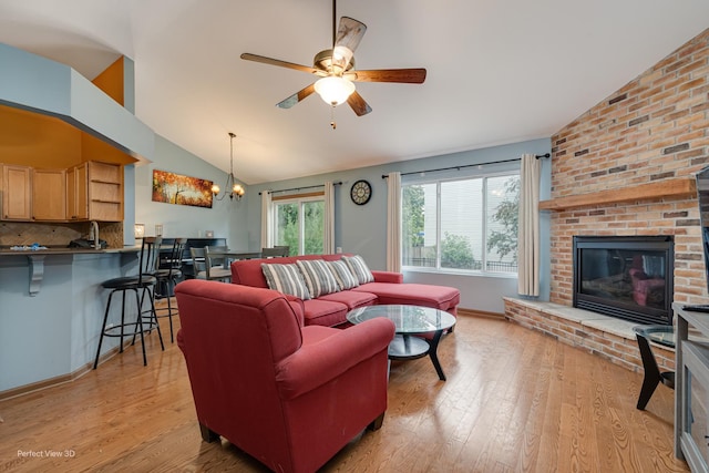 3018 Coastal Dr, Aurora, IL 60503 - living area featuring lofted ceiling, a brick fireplace, a ceiling fan, light wood-style flooring, and a chandelier