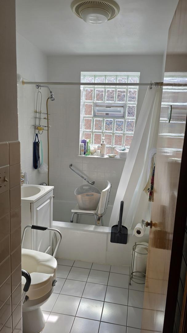 bathroom featuring shower / bath combo with shower curtain, healthy amount of natural light, tile patterned flooring, and vanity