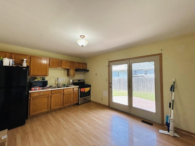 7710 E Sunset Dr, Wonder Lake, IL 60097 - kitchen with black appliances, brown cabinetry, and light wood-style flooring