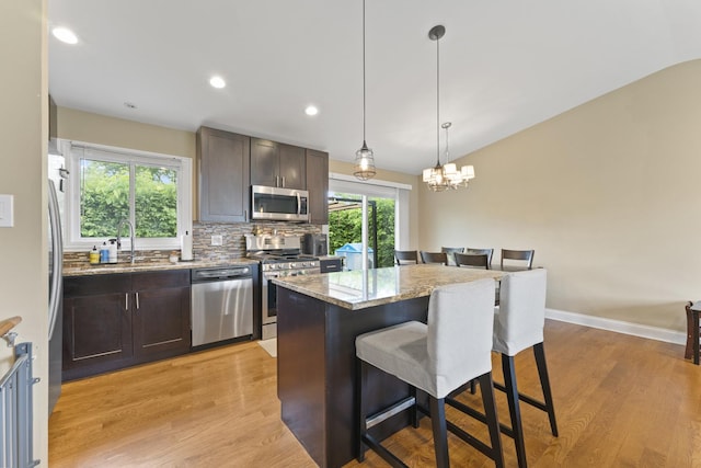 1122 N Cardinal Dr, Palatine, IL 60074 - kitchen with appliances with stainless steel finishes, a kitchen breakfast bar, light wood-style floors, dark brown cabinetry, and a sink
