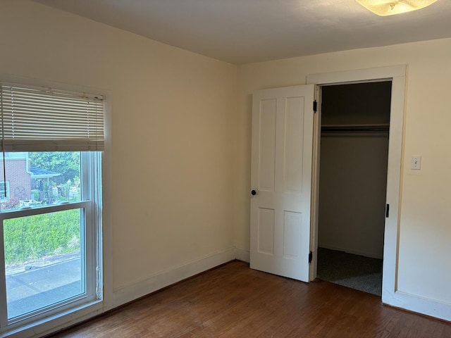 115 N Clay St, Mount Carroll, IL 61053 - unfurnished bedroom featuring dark wood-style floors, a closet, and baseboards