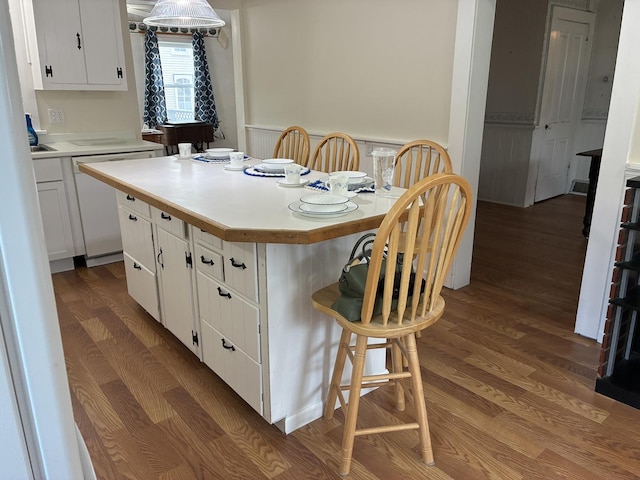 115 N Clay St, Mount Carroll, IL 61053 - kitchen with wood finished floors, white cabinetry, light countertops, a breakfast bar area, and dishwashing machine