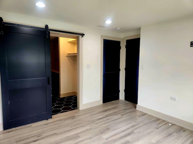 3601 W 123rd Pl, Alsip, IL 60803 - unfurnished bedroom with a barn door, light wood-style flooring, baseboards, a closet, and a walk in closet