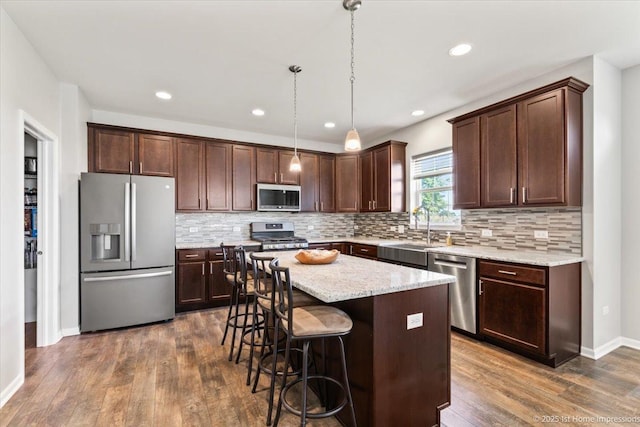 25734 Galway Ave, Plainfield, IL 60585 - kitchen with stainless steel appliances, a sink, dark brown cabinetry, dark wood-type flooring, and a kitchen island