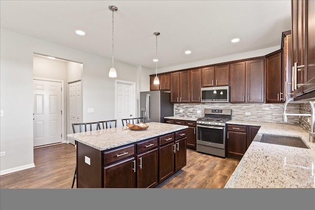 25734 Galway Ave, Plainfield, IL 60585 - kitchen with appliances with stainless steel finishes, dark brown cabinets, tasteful backsplash, a kitchen island, and recessed lighting