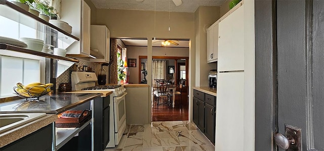 515 E Main St E, Amboy, IL 61310 - kitchen featuring white gas stove, ceiling fan, light marble finish flooring, decorative backsplash, and white cabinetry