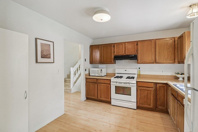 1705 N Donovan St, Mchenry, IL 60050 - kitchen with white appliances, under cabinet range hood, brown cabinetry, light wood finished floors, and light countertops