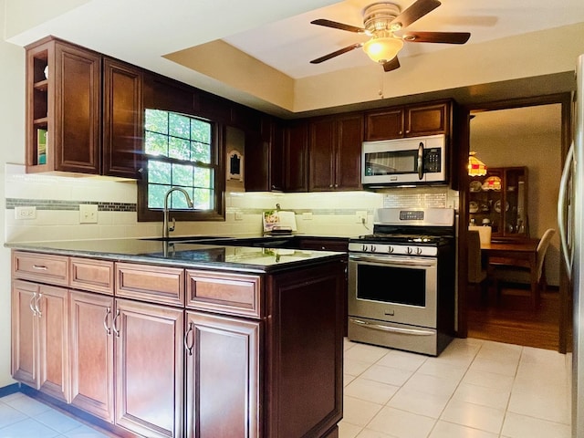 17581 W Summit Dr, Grayslake, IL 60030 - kitchen with stainless steel appliances, dark countertops, light tile patterned floors, decorative backsplash, and a ceiling fan