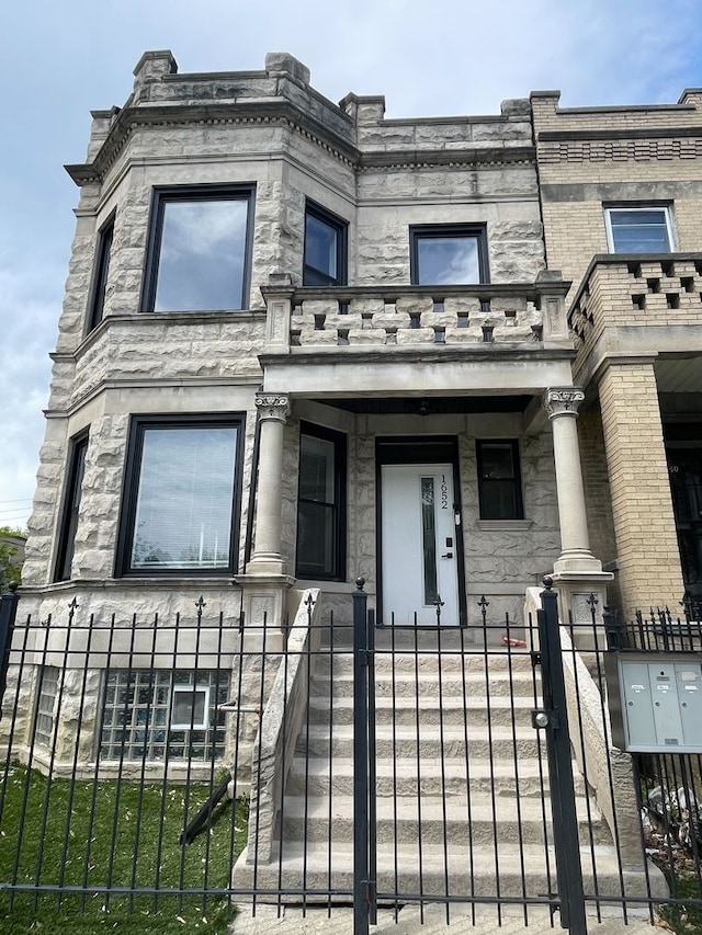 1652 S Ridgeway Ave, Chicago, IL 60623 - view of front of property with a fenced front yard, a balcony, and stone siding