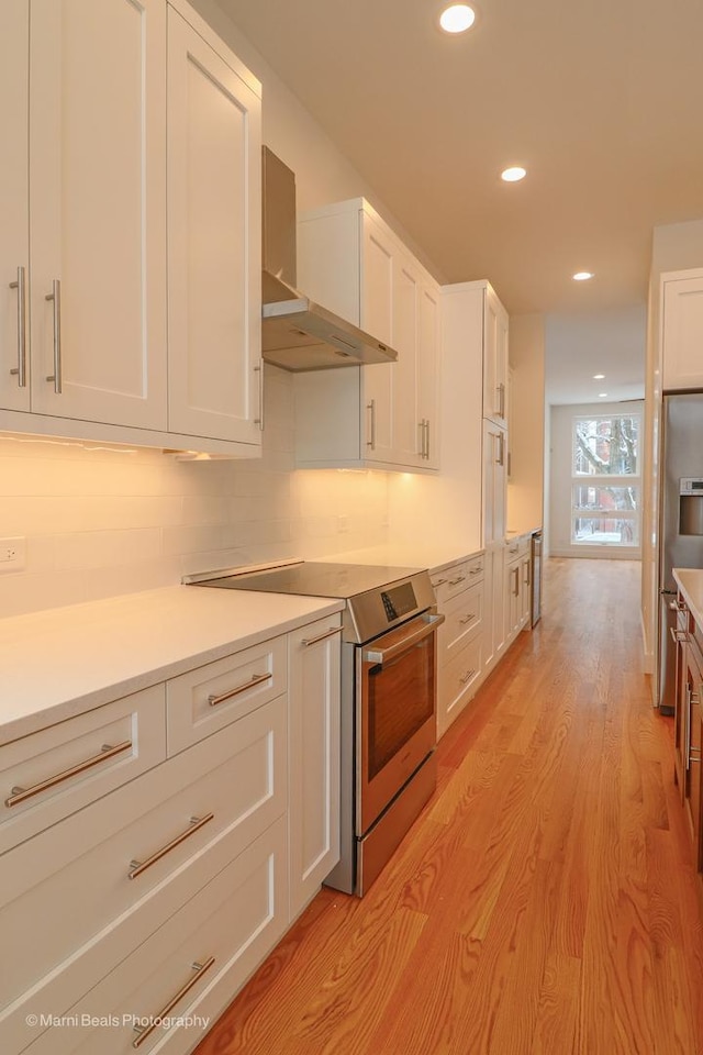 6123 S Ellis Ave, Chicago, IL 60637 - kitchen with stainless steel electric range, wall chimney exhaust hood, white cabinets, light wood-style flooring, and recessed lighting
