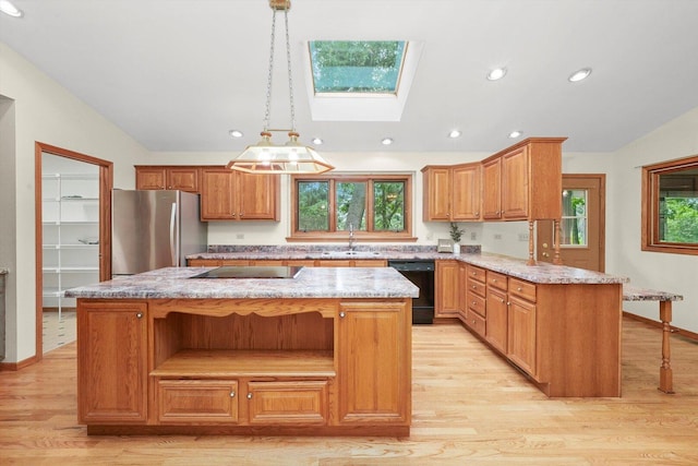 9316 Pine Needle Pass, Bull Valley, IL 60097 - kitchen with black appliances, a skylight, lofted ceiling, a center island, and light wood-style flooring