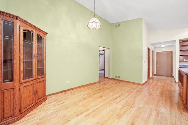 9316 Pine Needle Pass, Bull Valley, IL 60097 - unfurnished living room with high vaulted ceiling, light wood-type flooring, and a chandelier