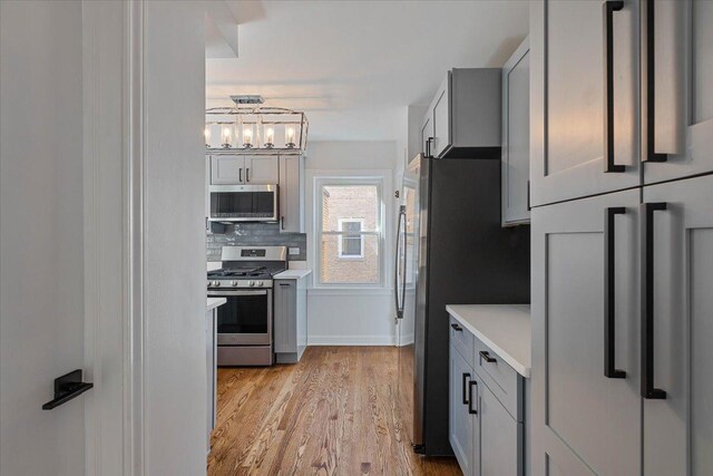 7241 N Kilpatrick Ave, Lincolnwood, IL 60712 - kitchen featuring stainless steel appliances, light countertops, backsplash, light wood finished floors, and gray cabinetry