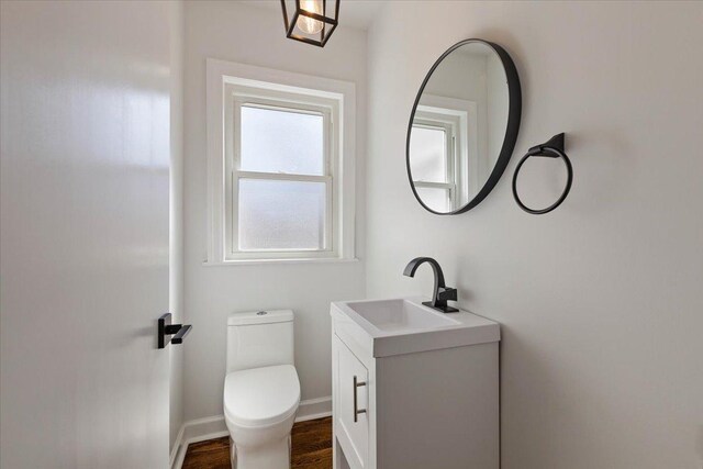 7241 N Kilpatrick Ave, Lincolnwood, IL 60712 - half bathroom with vanity, toilet, wood finished floors, and baseboards