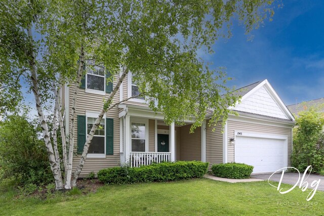1943 Lily Ln, Round Lake, IL 60073 - view of front of home with covered porch, an attached garage, a front lawn, and concrete driveway