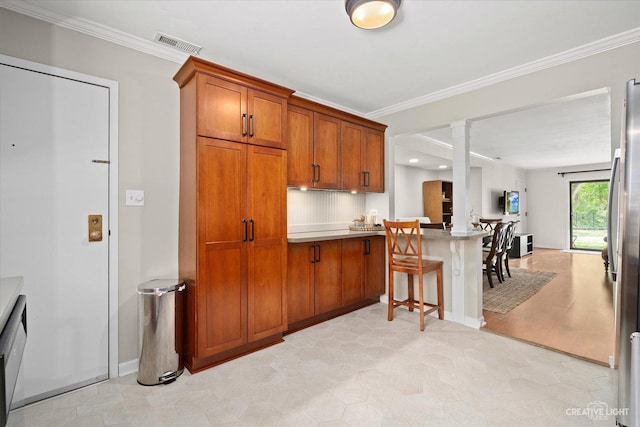 506 Taylor Ave Unit A, Glen Ellyn, IL 60137 - kitchen with brown cabinetry, decorative columns, crown molding, a peninsula, and a breakfast bar area