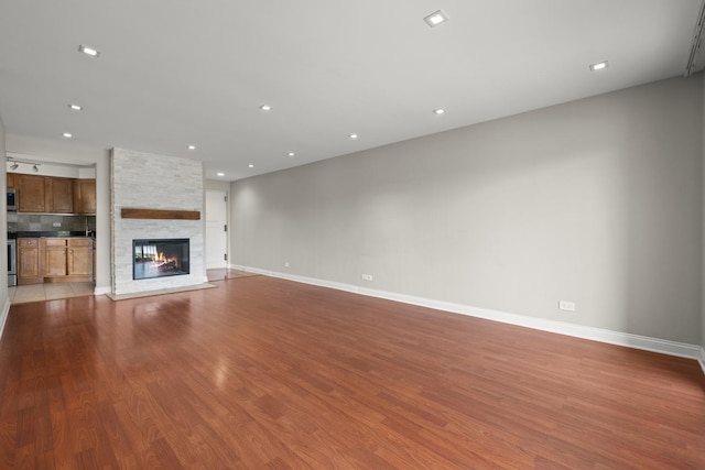 5332 N Delphia Ave Unit 108, Chicago, IL 60656 - unfurnished living room with wood finished floors, baseboards, a stone fireplace, and recessed lighting