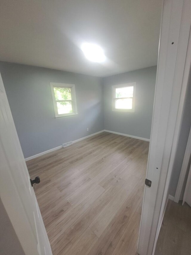 3025 Central Ave, Rockford, IL 61102 - unfurnished bedroom featuring light wood-type flooring, multiple windows, and baseboards