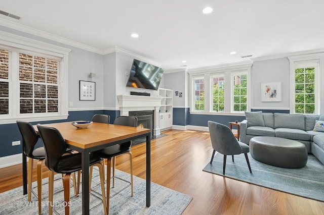 2338 W Roscoe St Unit 2E, Chicago, IL 60618 - dining space featuring a warm lit fireplace, wood finished floors, recessed lighting, and crown molding
