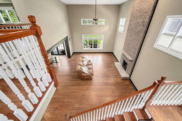 808 Maple Ave, Downers Grove, IL 60515 - staircase featuring plenty of natural light, a high ceiling, a fireplace, wood finished floors, and ceiling fan