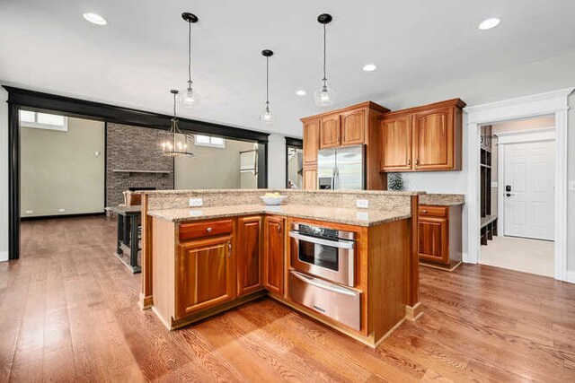 808 Maple Ave, Downers Grove, IL 60515 - kitchen featuring stainless steel appliances, a warming drawer, brown cabinetry, a fireplace, and light wood-type flooring
