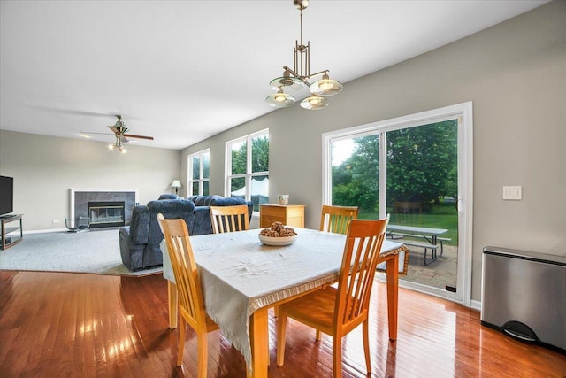 2585 Lambert Dr, Aurora, IL 60503 - dining area featuring a glass covered fireplace, wood finished floors, a ceiling fan, and a chandelier