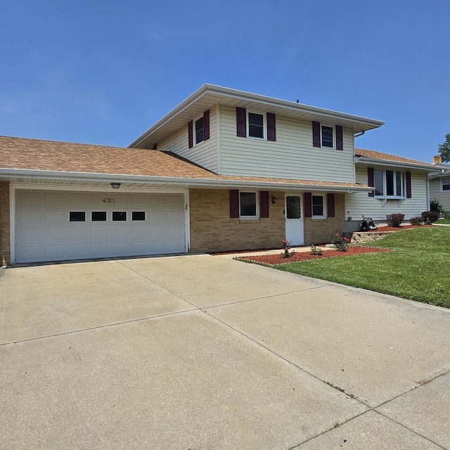 421 W 1st St, Stillman Valley, IL 61084 - split level home featuring concrete driveway, an attached garage, brick siding, and a front yard