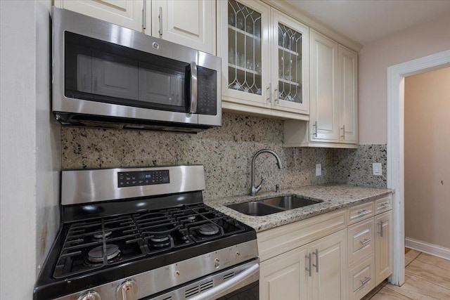 8353 N Drake Ave, Skokie, IL 60076 - kitchen with appliances with stainless steel finishes, a sink, tasteful backsplash, glass insert cabinets, and light stone counters