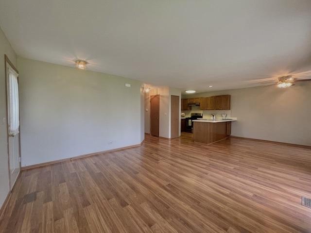 304 University Ln Unit 5, Elk Grove Village, IL 60007 - kitchen featuring a peninsula, brown cabinets, appliances with stainless steel finishes, light wood-style floors, and light countertops