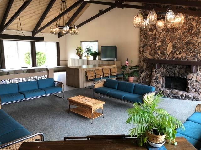 15713 Orlan Brook Dr Unit 97, Orland Park, IL 60462 - living room featuring a chandelier, high vaulted ceiling, beamed ceiling, a stone fireplace, and carpet floors