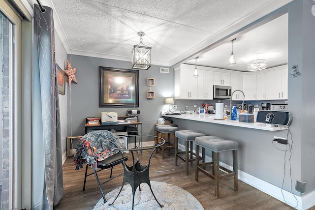 15713 Orlan Brook Dr Unit 97, Orland Park, IL 60462 - kitchen with stainless steel microwave, wood finished floors, a breakfast bar, crown molding, and white cabinets