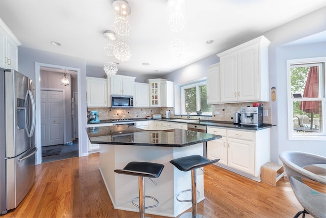 647 Oak Ln, South Elgin, IL 60177 - kitchen featuring appliances with stainless steel finishes, white cabinetry, a kitchen breakfast bar, light wood-type flooring, and tasteful backsplash