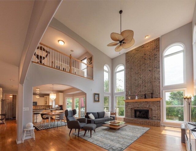 647 Oak Ln, South Elgin, IL 60177 - living area with a towering ceiling, arched walkways, a ceiling fan, wood finished floors, and a brick fireplace
