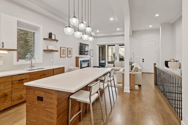 1304 N Hoyne Ave Unit 1, Chicago, IL 60622 - kitchen with a sink, brown cabinets, a breakfast bar, modern cabinets, and a center island