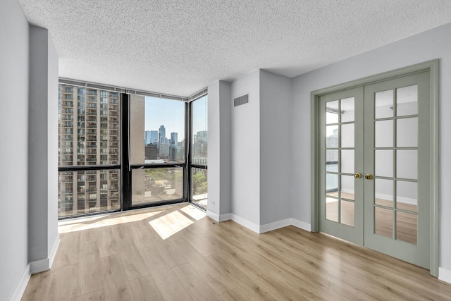 1122 N Clark St Unit 1710, Chicago, IL 60610 - unfurnished room with french doors, wood finished floors, a view of skyline, a textured ceiling, and baseboards