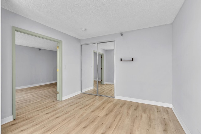 1122 N Clark St Unit 1710, Chicago, IL 60610 - unfurnished bedroom featuring light wood-style floors, a closet, a textured ceiling, and baseboards