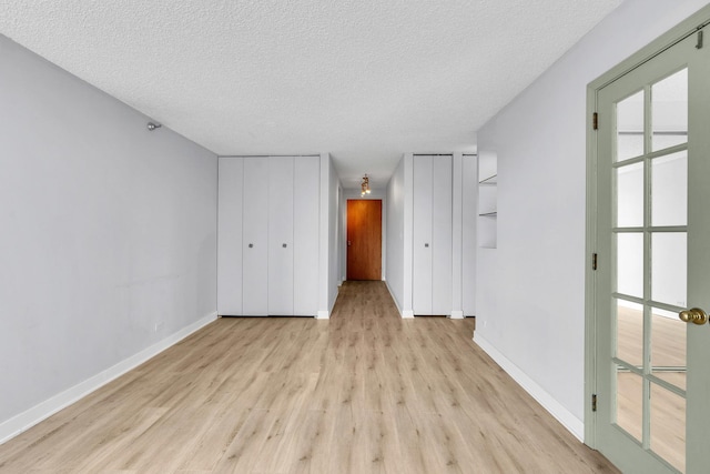 1122 N Clark St Unit 1710, Chicago, IL 60610 - unfurnished bedroom with multiple closets, light wood-style flooring, a textured ceiling, and baseboards