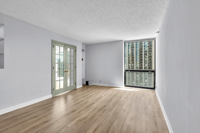 1122 N Clark St Unit 1710, Chicago, IL 60610 - unfurnished room with a textured ceiling, wood finished floors, a wall of windows, french doors, and baseboards