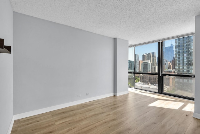 1122 N Clark St Unit 1710, Chicago, IL 60610 - empty room with expansive windows, wood finished floors, healthy amount of natural light, a skyline view, and a textured ceiling