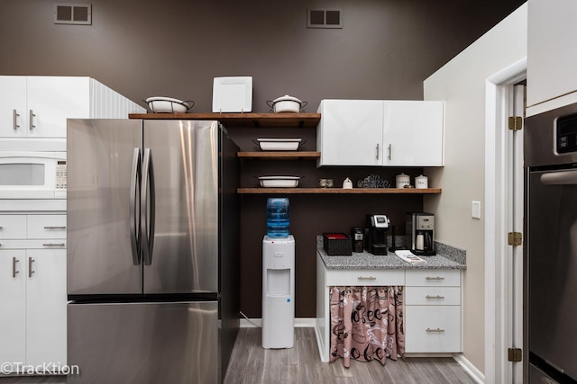 2609 Dougall Rd, Joliet, IL 60433 - kitchen with stainless steel appliances, wood finished floors, open shelves, white cabinetry, and light stone counters